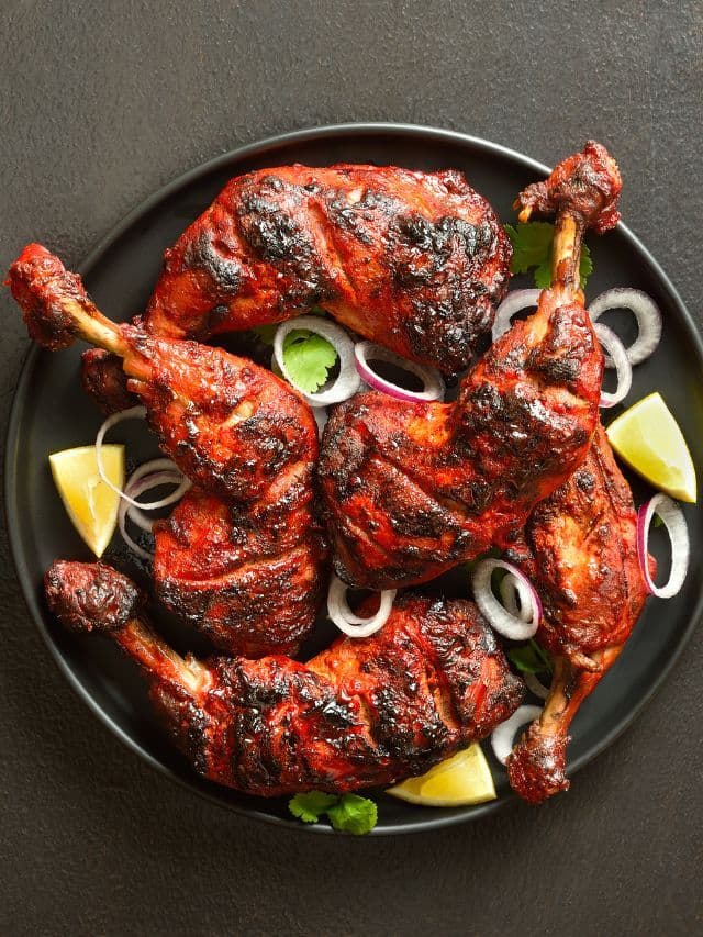 A whole tandoori chicken plated with onion and lime